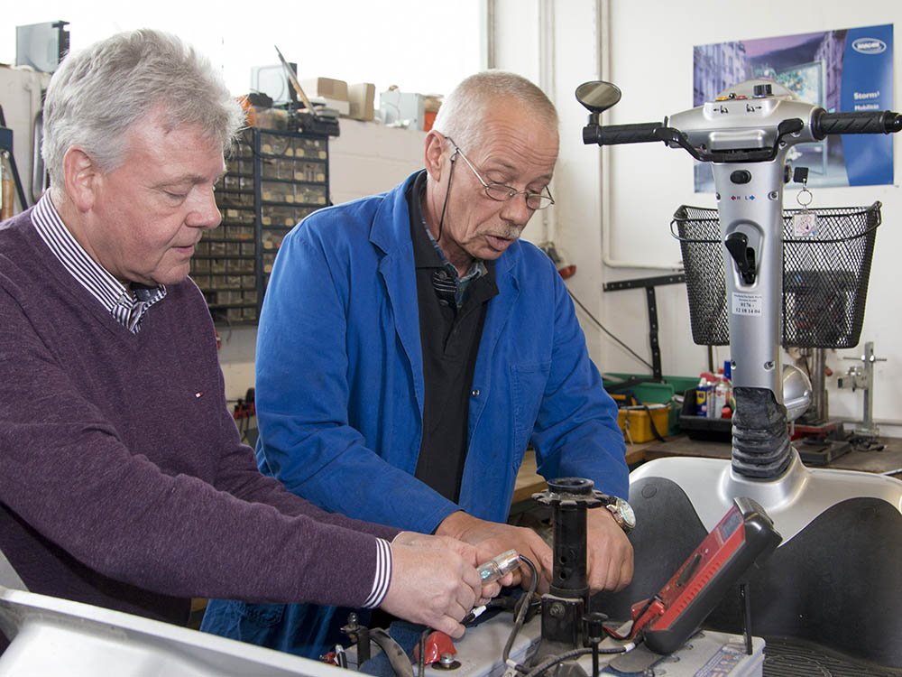 Elektromobil-Werkstattservice bei Petsch Rehatechnik Mitarbeiter von Petsch Rehatechnik führen Wartung und Reparatur an einem Elektromobil in der firmeneigenen Werkstatt durch